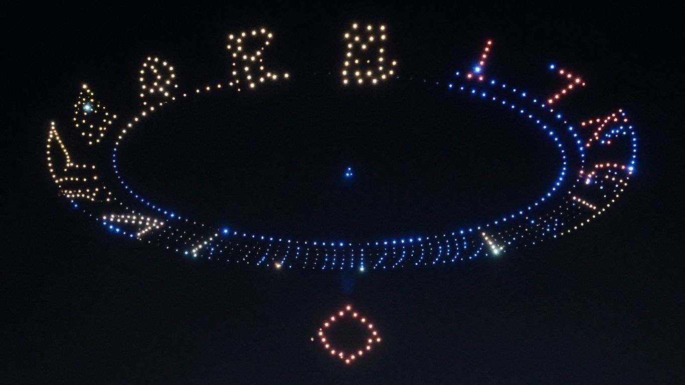 Drone light show forming patterns in the night sky.